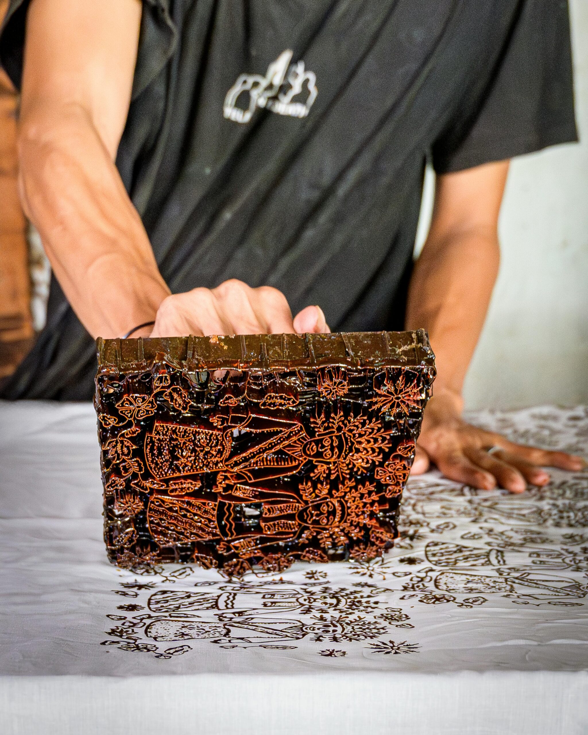 Artisan demonstrates batik printing technique in Jakarta workshop.