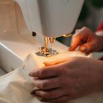 Detailed view of sewing process with hands guiding fabric on a machine.
